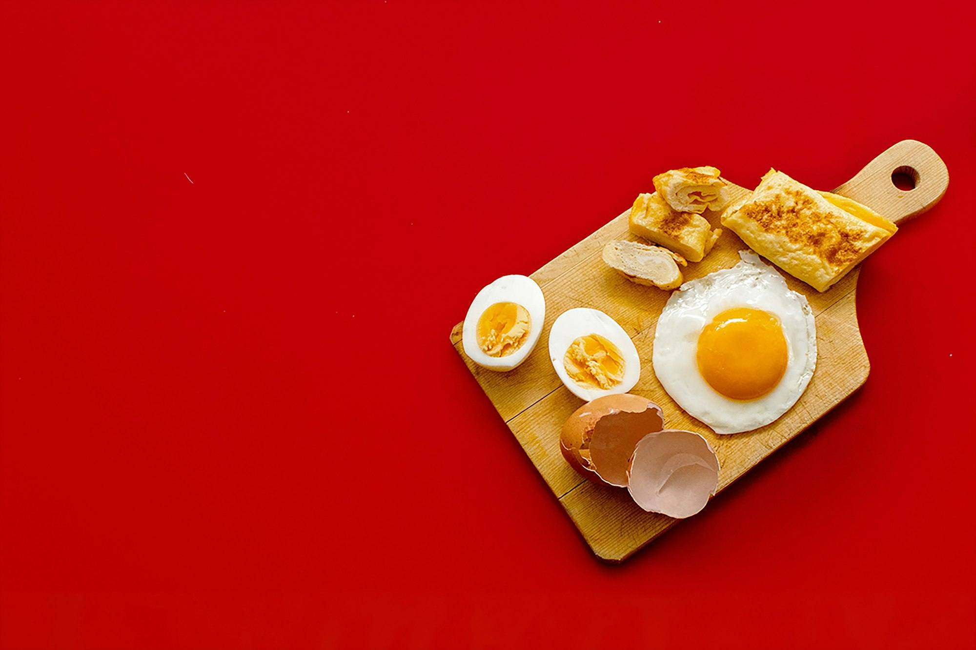 Eggs and toast on a cutting board against a red background