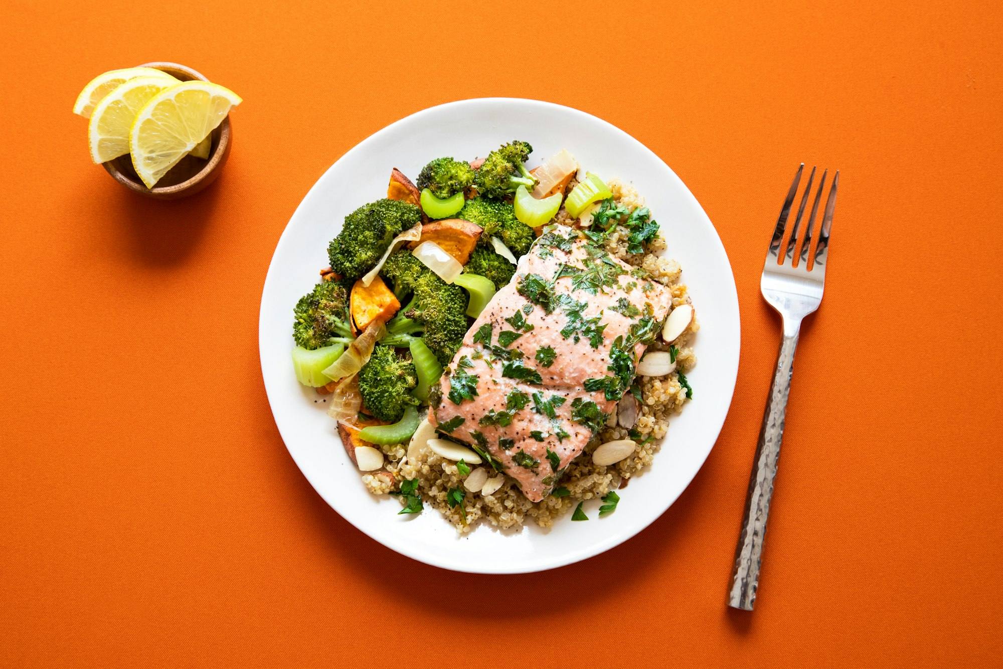 A salmon and greens plate on an orange table